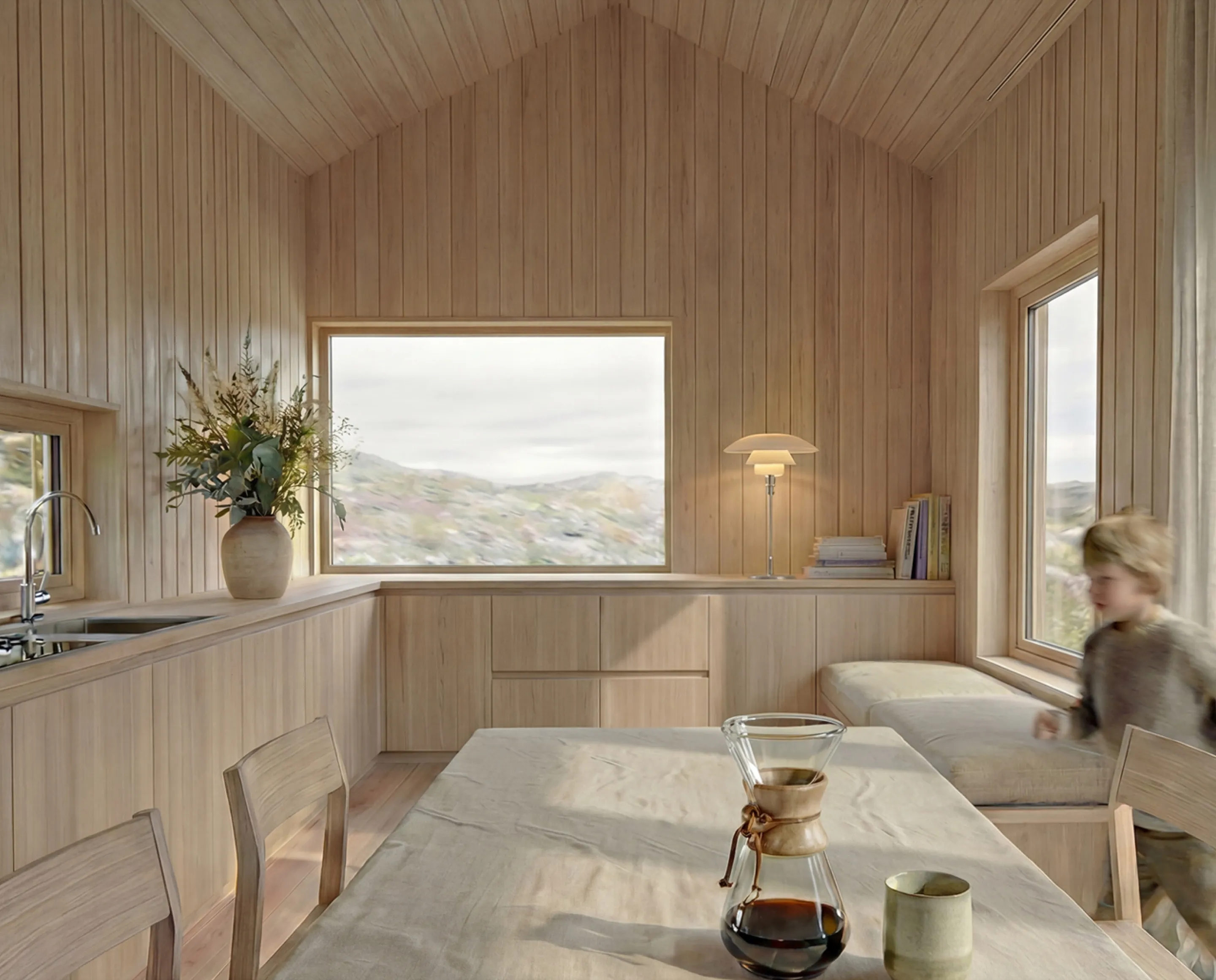 A bright cabin interior in light wood, with a dining table and a view of the mountains