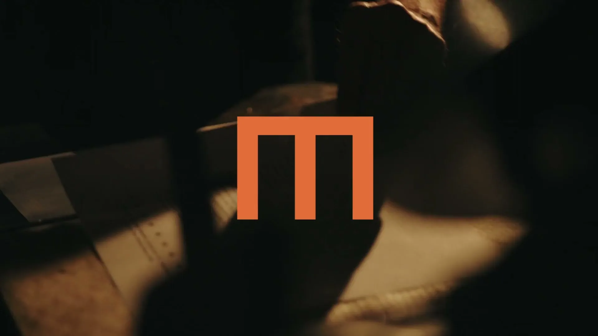Omhu’s orange m symbol in moving light and shadow