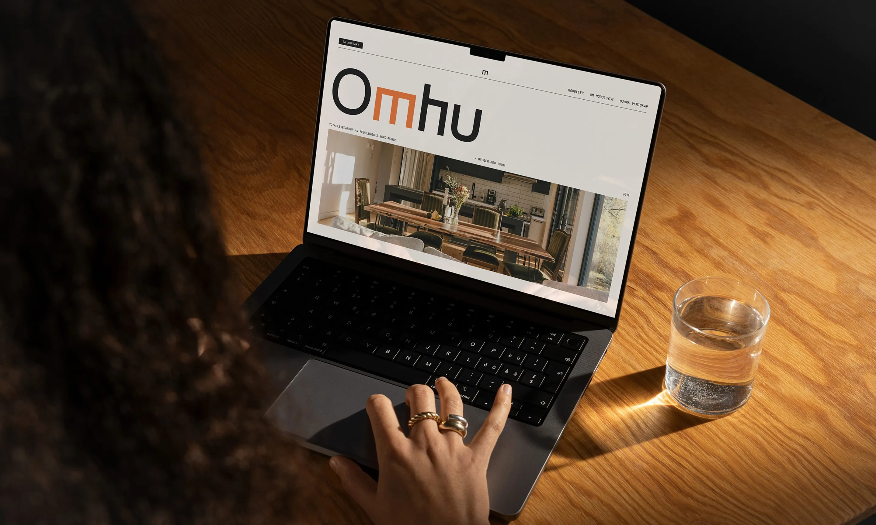 Hands typing on a laptop that shows Omhu’s website