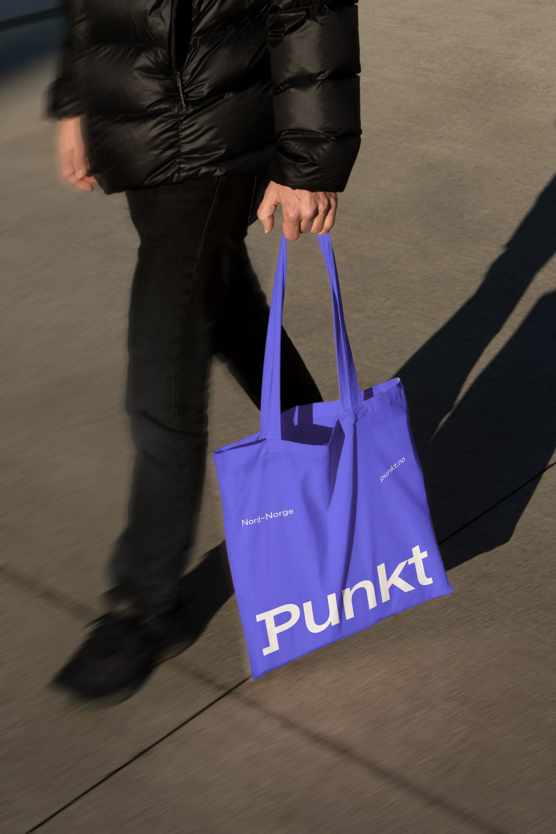 En person som går med et lilla Punkt-handlenett