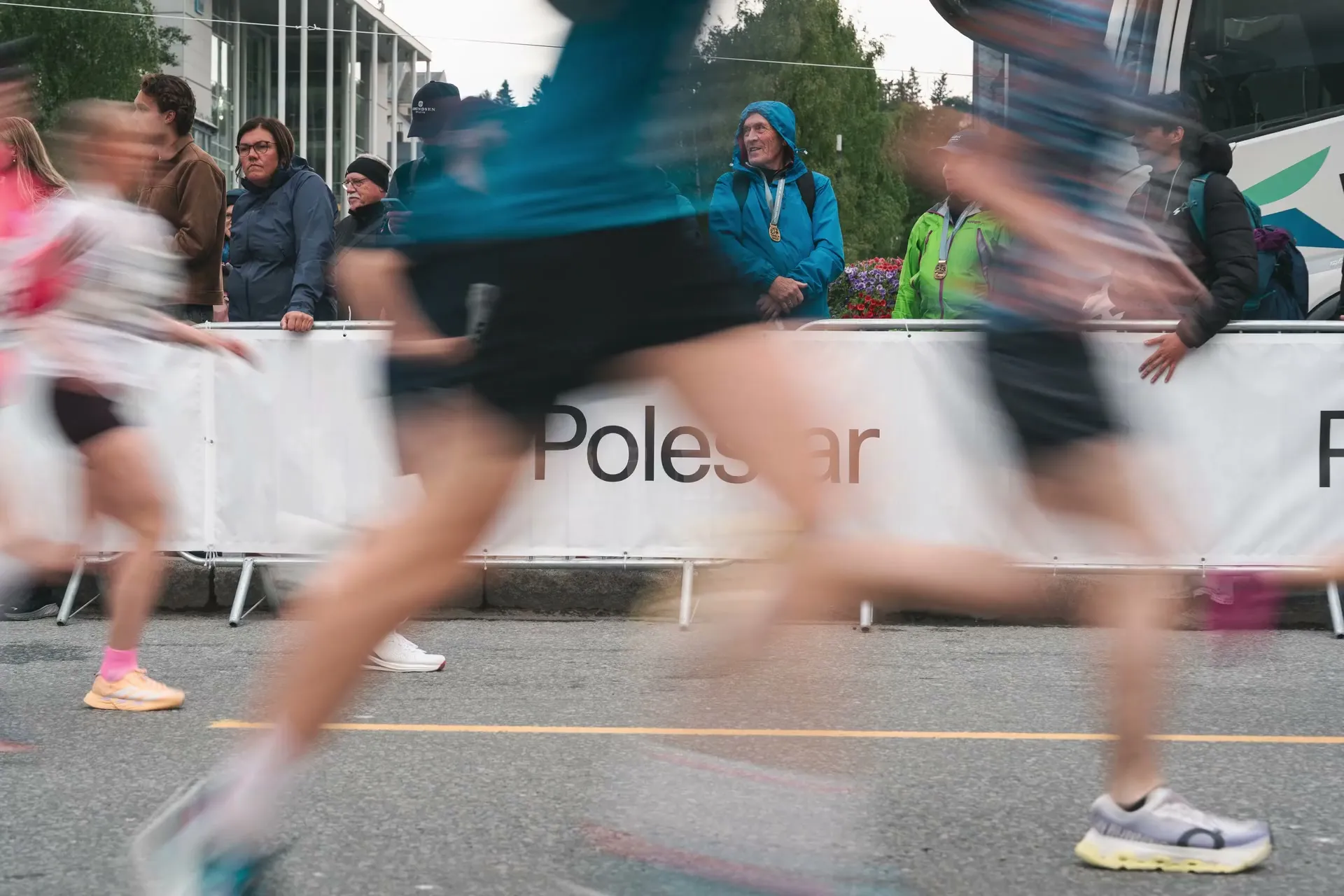 Løpere suser forbi et Polestar-banner mens folk ser på bak sperringen