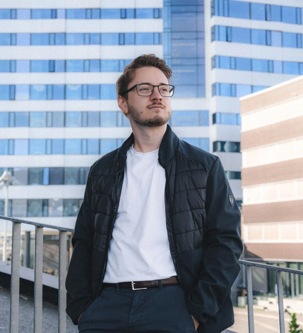 Alexandru på et tak, med en hvit kontorblokk med blå vinduer bak seg