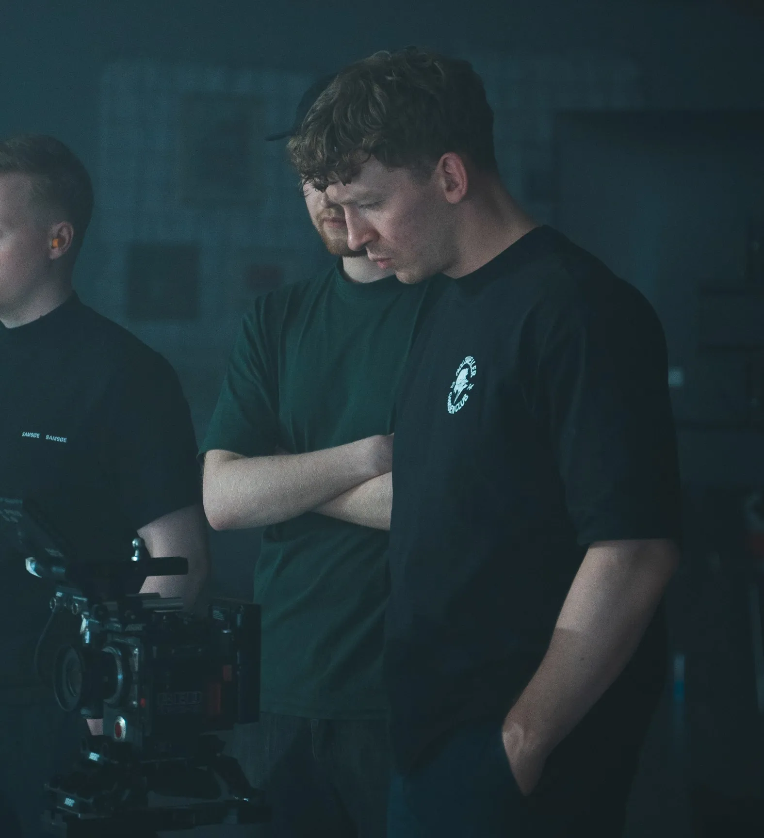 Trygve ser ned på kameraet på et filmsett, sammen med to andre